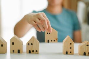 Woman,Selecting,And,Arranging,Wooden,House,Models,,Concept,Of,Real
